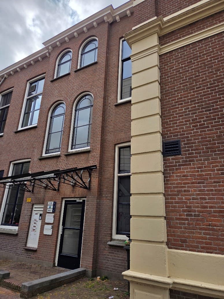 De ingang van Nedanza in Delft, een zwarte deur met naambordjes